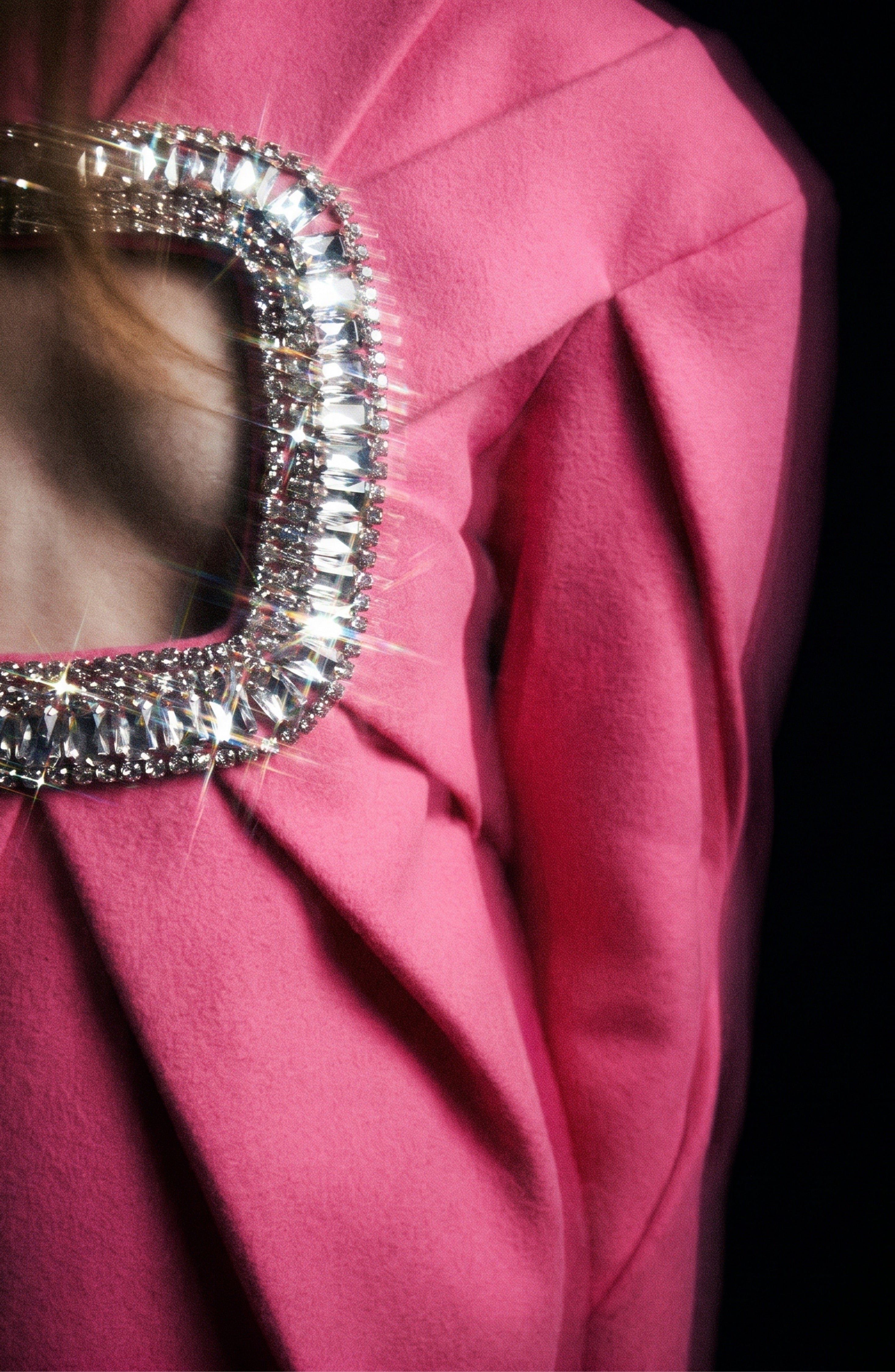 A person wearing the LOULOU Crystal Cutout Mini Dress in vibrant fuchsia, featuring a square open back accented with a sparkling jeweled trim.