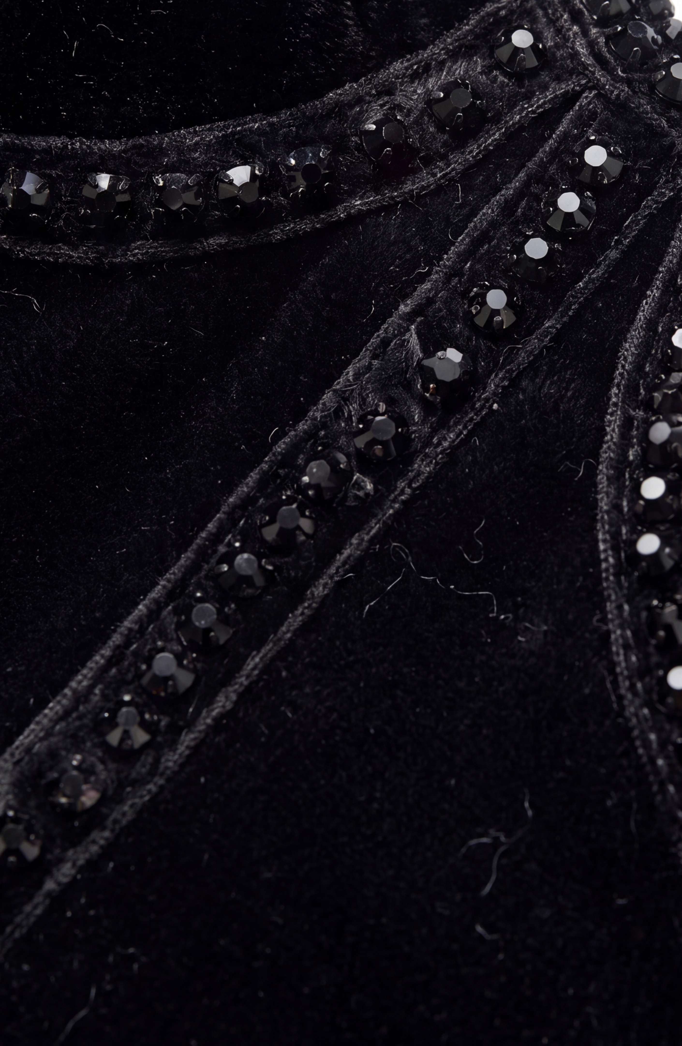 Close-up of the LOULOU Crystal Velvet Corset T-Shirt, featuring black velvet fabric adorned with rows of small, shiny black beads sewn along raised seams, evoking the look of a corset.