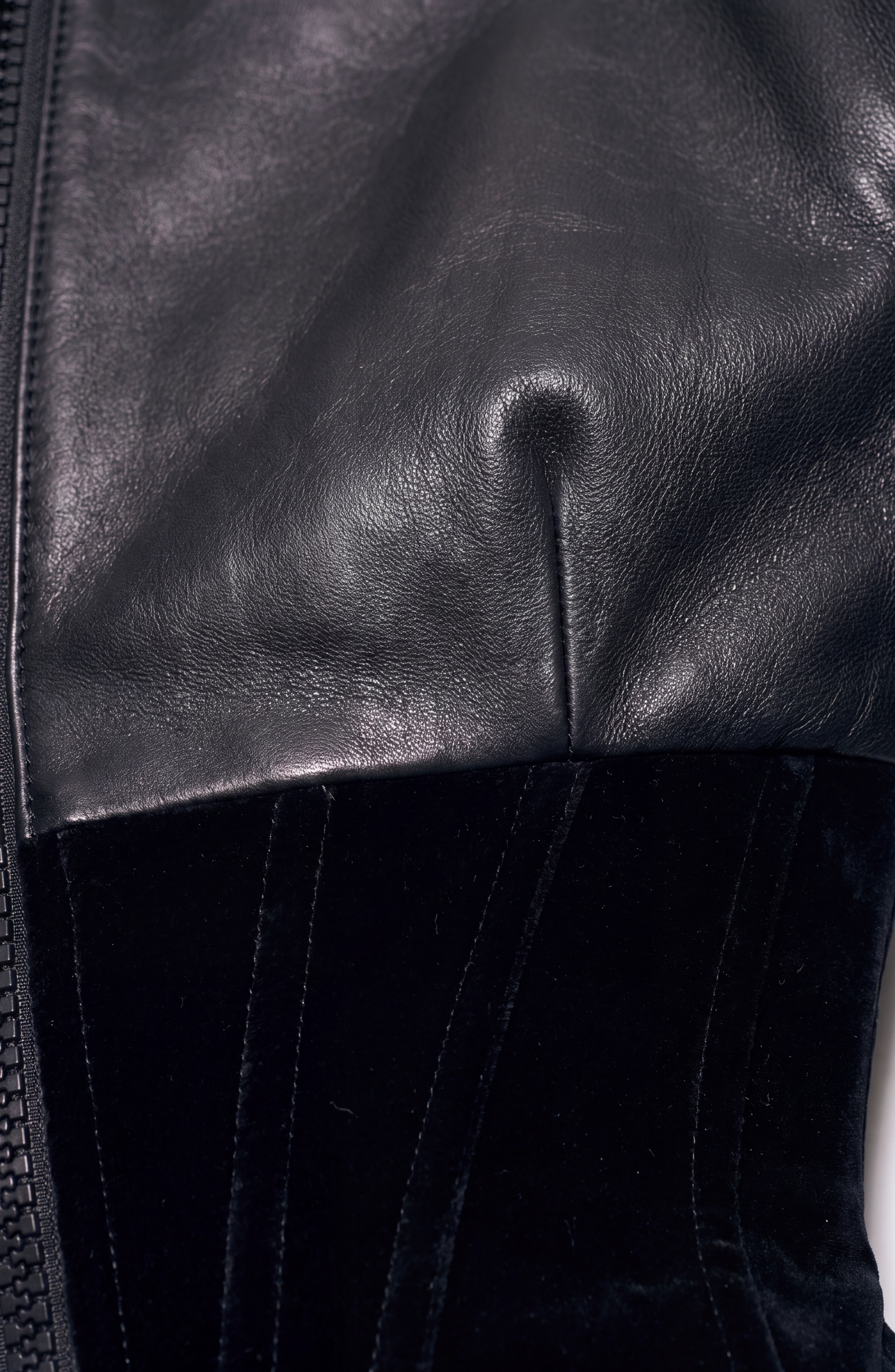 Close-up of the LOULOU Leather And Velvet Corset Jacket highlights the contrast between its smooth black leather and soft velvet panels, showcasing visible stitching and a zipper along the left side—subtle corset-inspired details are elegantly integrated into its design.