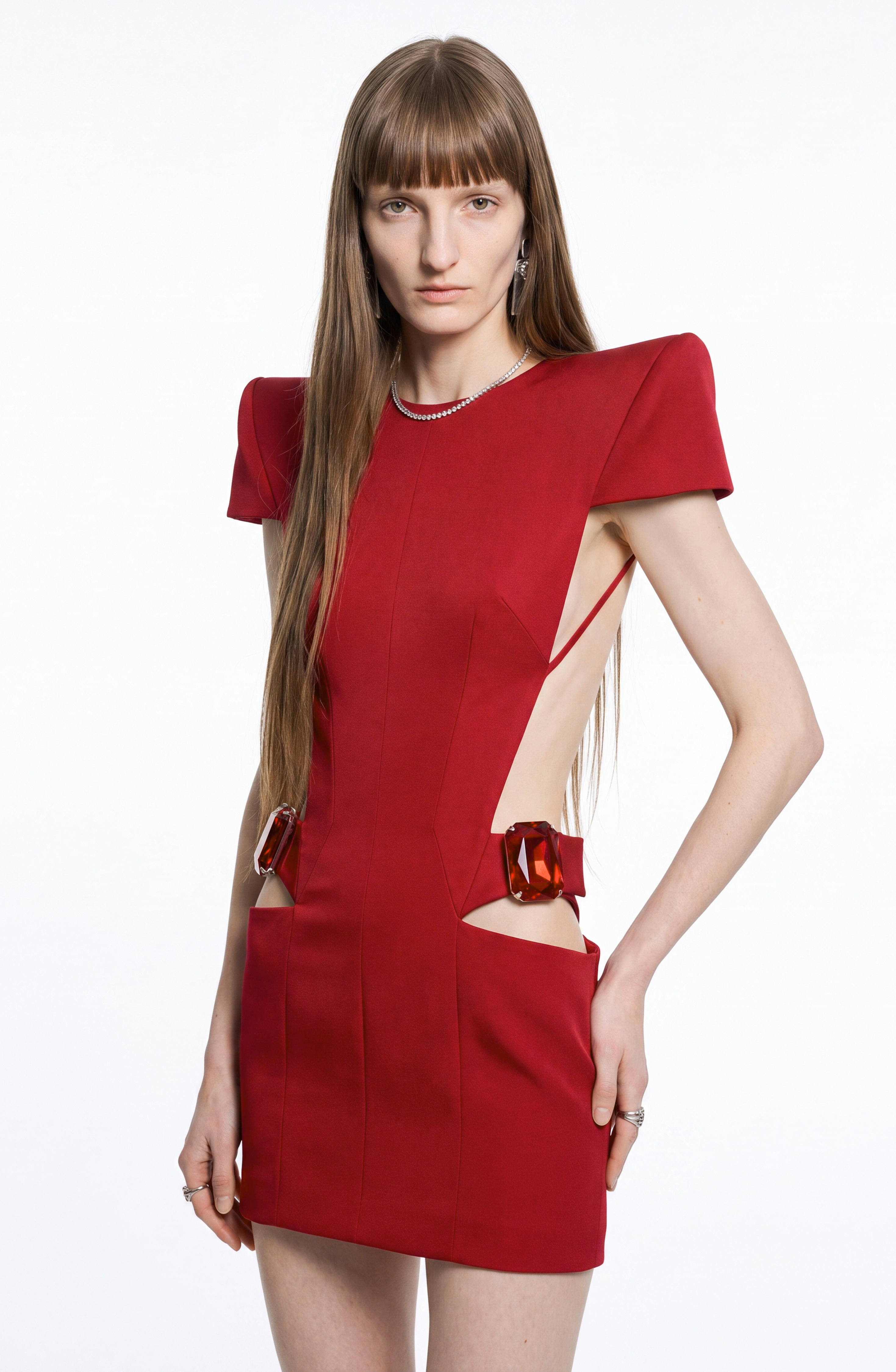 A person with long brown hair wears the LOULOU Crystal-Embellished Cutout Mini Dress, featuring padded shoulders and cut-out sides, posing against a plain white background.