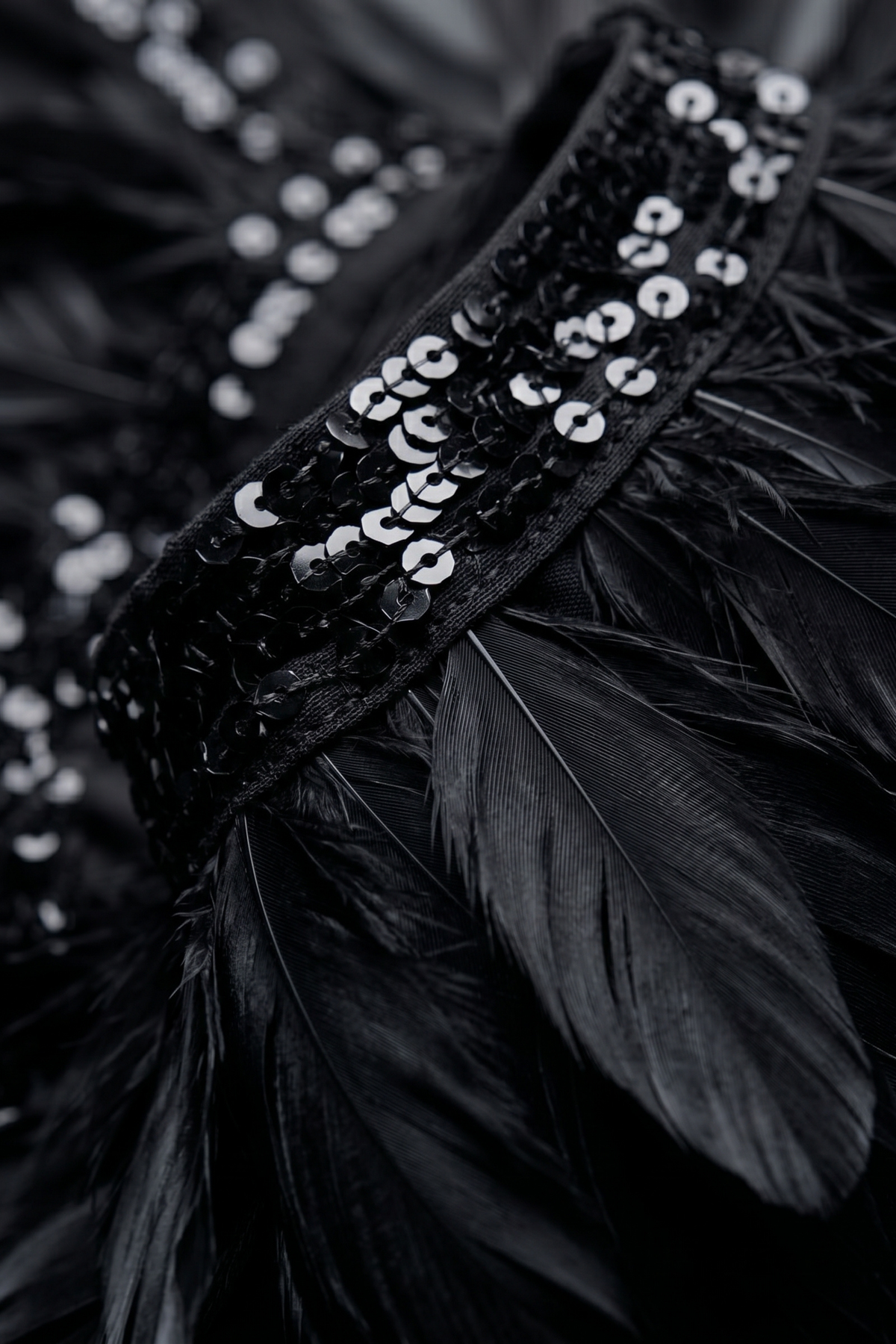 Detail view of the LOULOU Black Feather Sequin Peplum Top with feather peplum and decorative black band with shiny sequin embellishments.