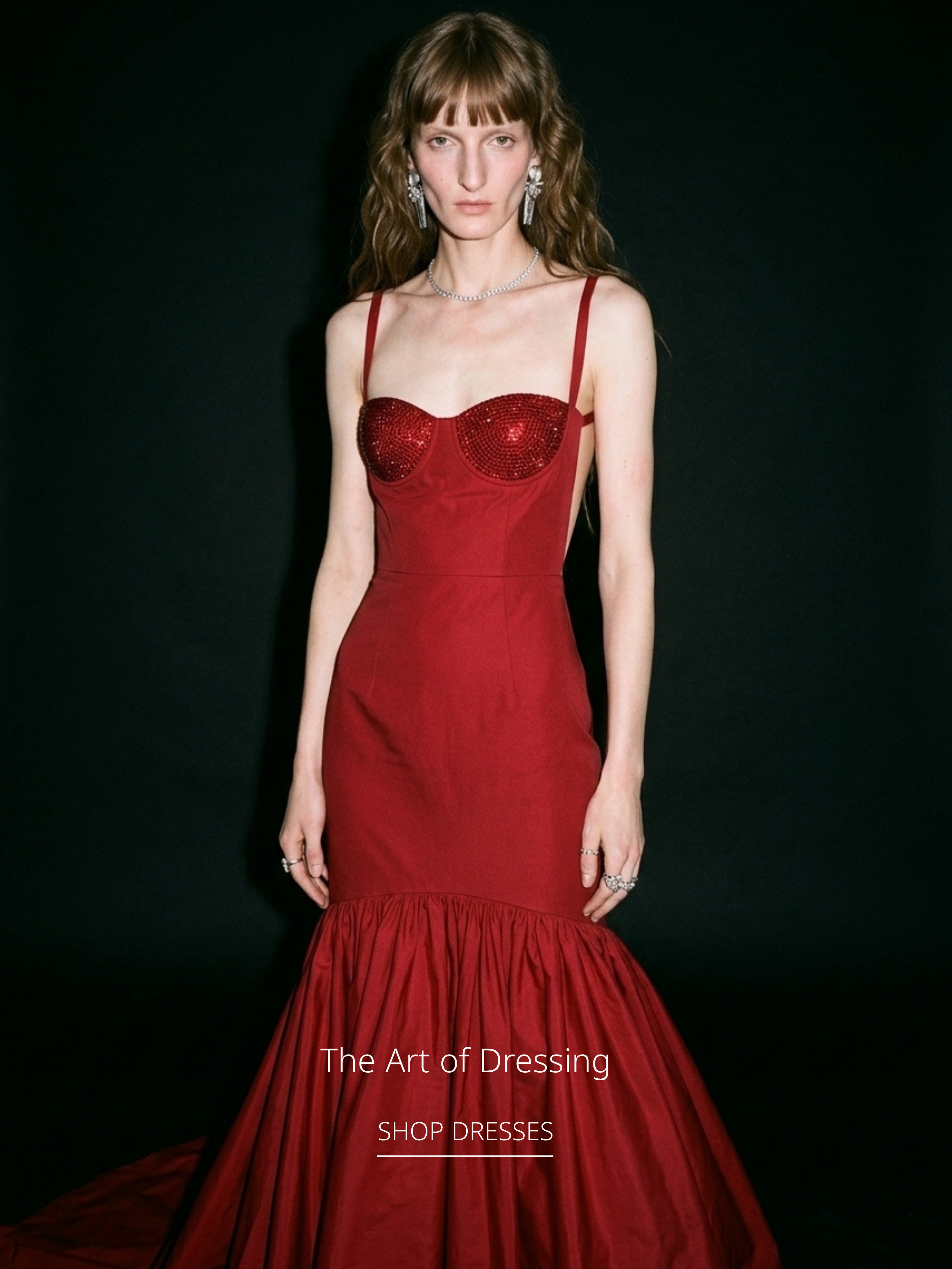 Model wearing a red crystal corset gown from the LOULOU collection, photographed against a black backdrop.