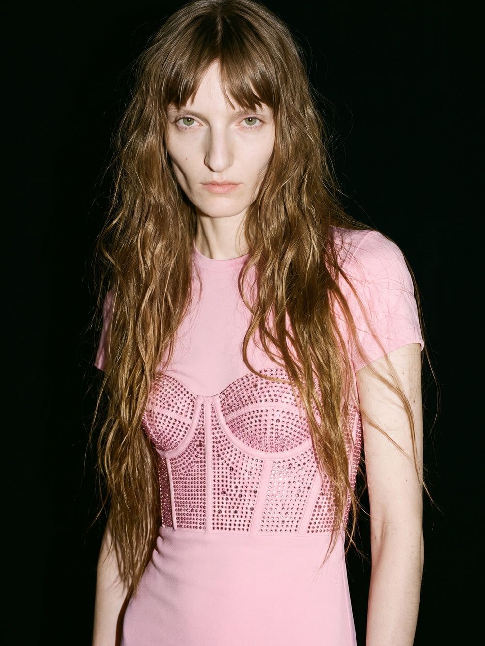 Model wearing a blush pink embellished designer dress from the LOULOU New Arrivals collection against a black backdrop.