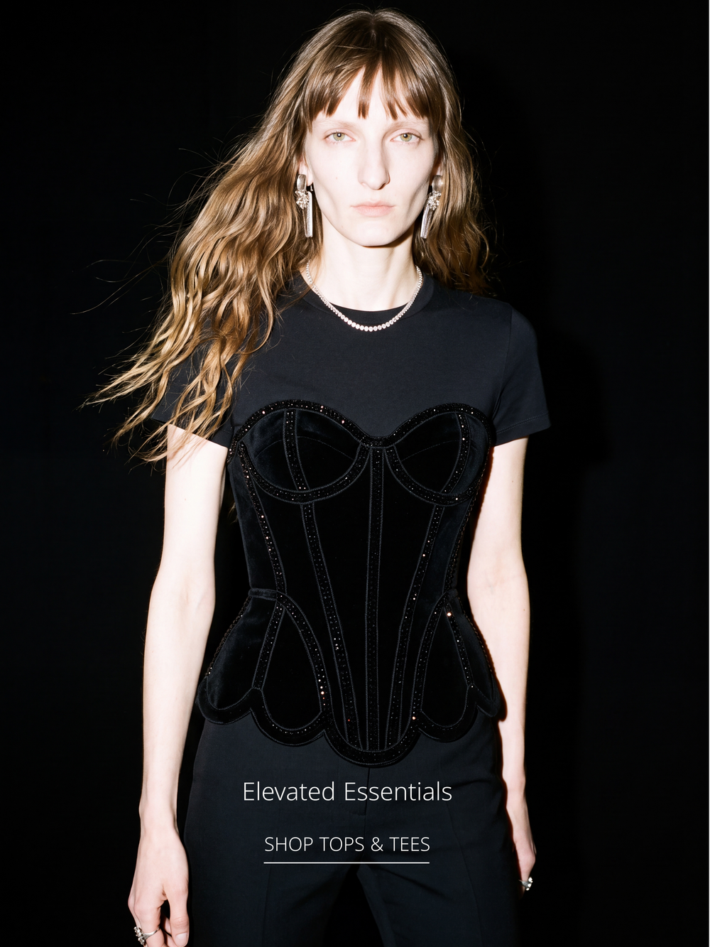 Model wearing a black embellished corset T-shirt from the LOULOU Tops & Tees collection against a black backdrop.